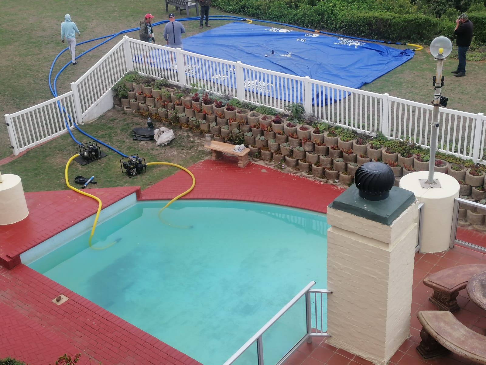 Pumps and hoses moving pool water into an Aston Bay water storage bladder