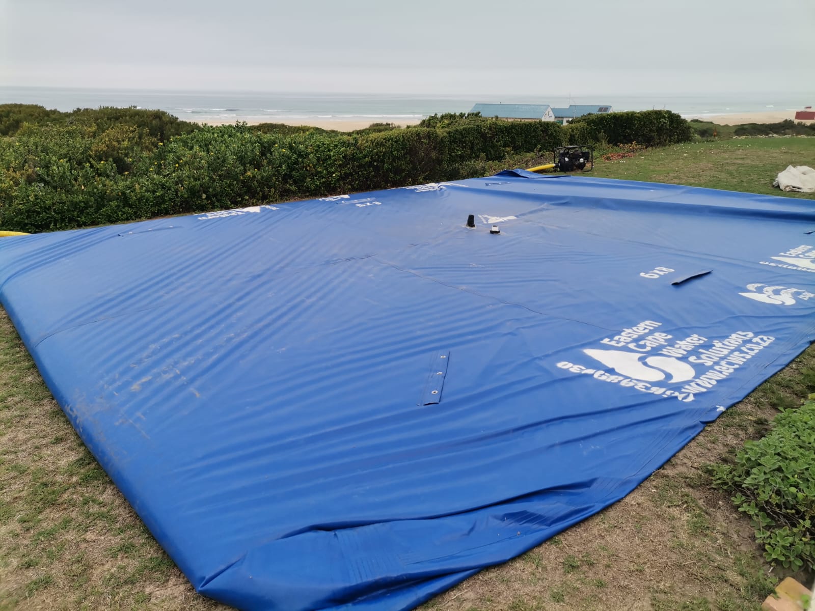 6x9 water storage bladder laid out on an Aston Bay beachfront lawn before filling