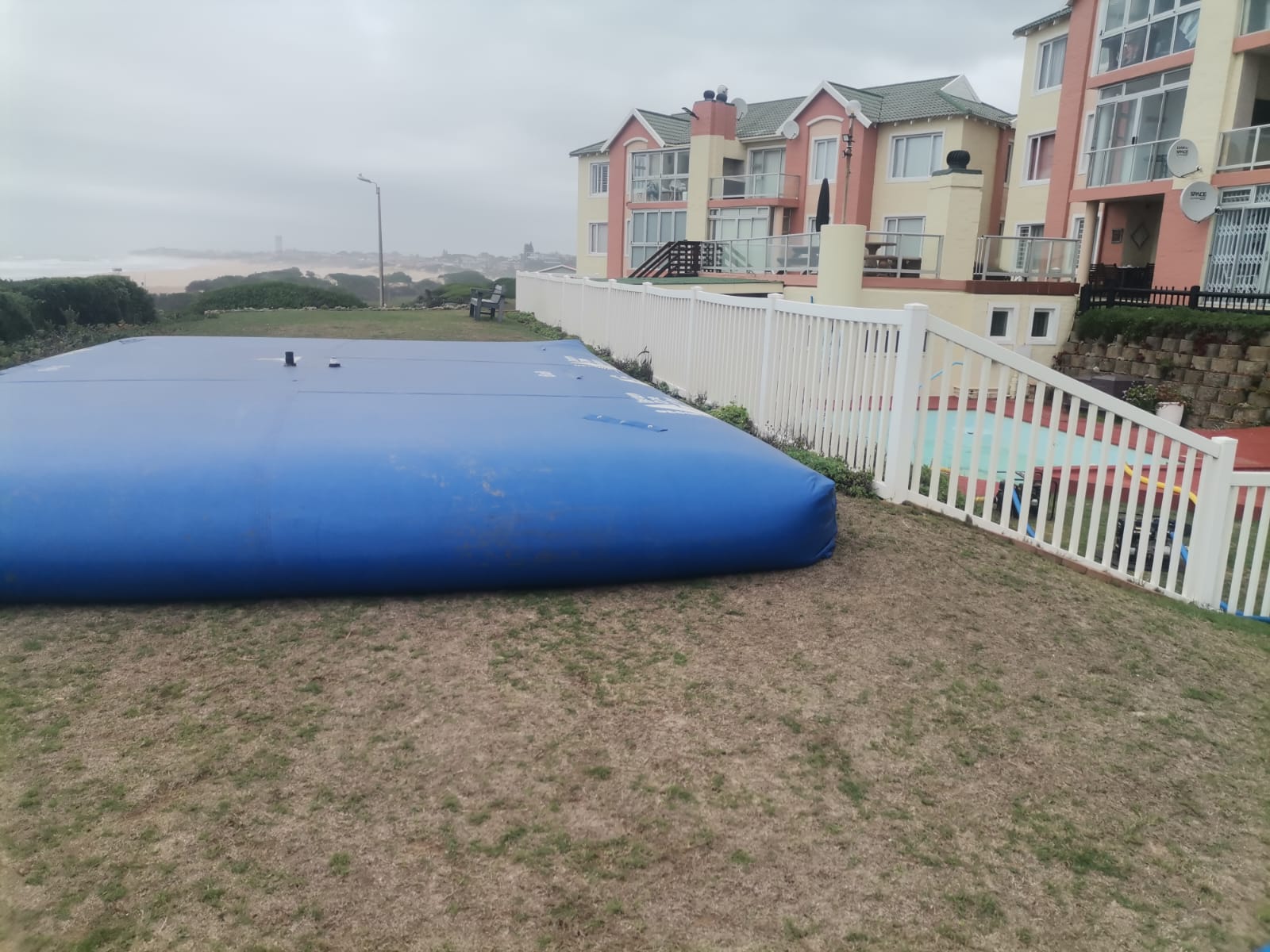Water storage bladder holding pool water on a dune-side lawn in Aston Bay