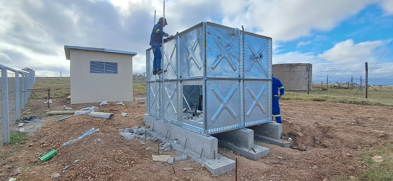 Sectional galvanised steel water tank being erected at eZambuzane near Dutywa, Eastern Cape
