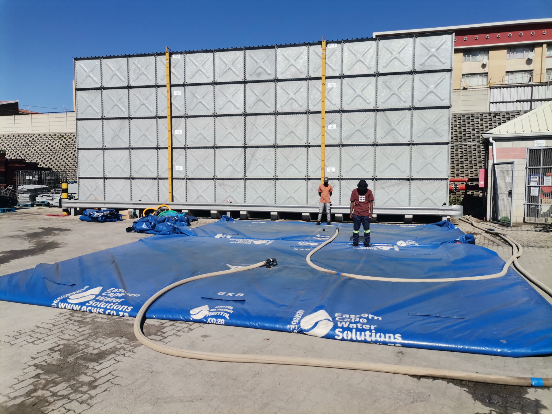 ECWS team filling 6x8 water storage bladders on a commercial site