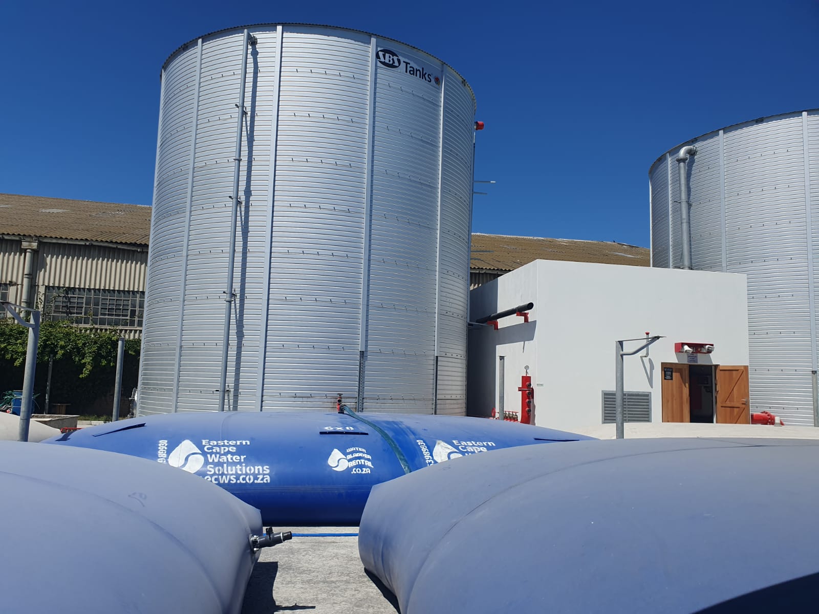Water bladders providing temporary storage beside large steel reservoir tanks